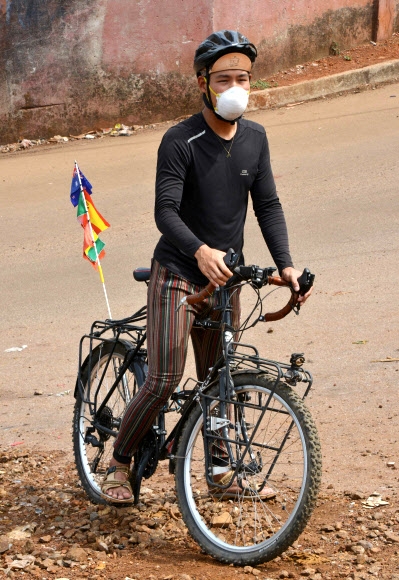 자전거로 세계일주 중인 레이몬드 리가 지난 30일 아프리카 기니의 거리에서 자전거와 함께 서 있다. 연합뉴스.