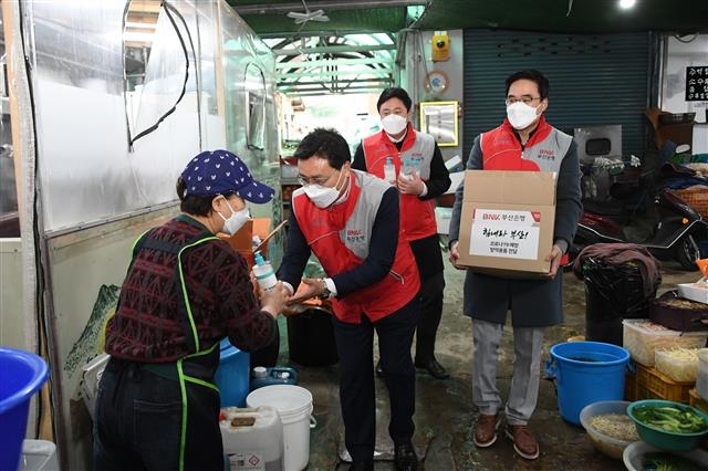 부산은행 직원들이 지난 2월 부산 연제구의 한 전통시장을 방문해 시장 상인들에게 마스크와 손세정제를 전달하고 있다. 부산은행 제공
