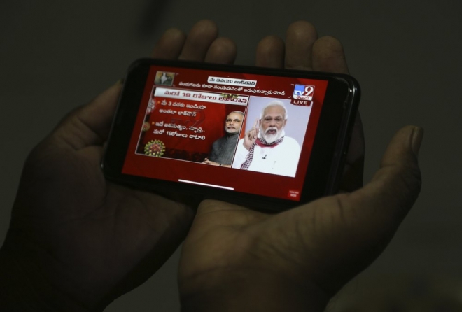 나렌드라 모디 인도 총리가 지난달 14일 코로나19 사태와 관련한 도시 봉쇄를 발표하는 동안 하이데라바드에 있는 한 남성이 자신의 휴대폰으로 모디 총리의 연설 동영상을 시청하는 모습. AP 자료 사진