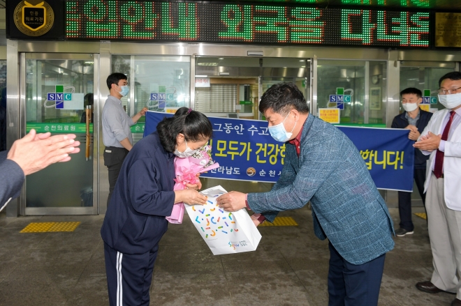 김병주 순천시 부시장이 코로나19 증상이 완치돼 대구로 귀향하는 60대 여성에게 꽃다발과 기념품을 전달하고 있다.