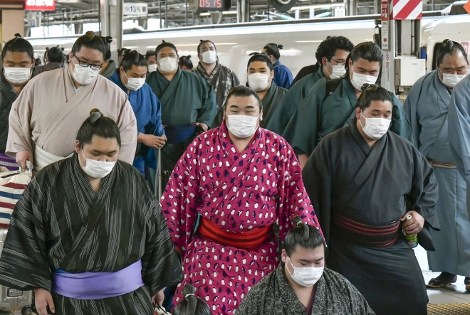 23일 일본의 스모 선수들이 마스크를 쓴 채 오사카의 한 지하철역에 들어서고 있다. 2020.2.23  AP 연합뉴스