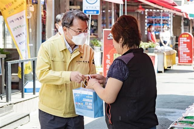 김선갑(왼쪽) 광진구청장이 지난 4일 능동로시장에서 한 시장 상인에게 ‘건강생활실천 자가 활동 꾸러미’를 전달하며 경기침체로 인한 고충을 듣고 있다. 광진구 제공