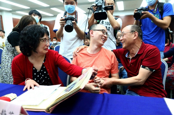 마오인(가운데)이 18일 중국 산시성 시안에서 진행된 기자회견 도중 친부모 마오젠징, 리징쥐와 상봉의 감격을 나누고 있다. 시안 AFP 연합뉴스