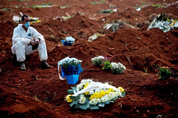 브라질 상파울루에 있는 남미 최대의 묘지인 빌라 포르모사의 관리인이 지난 18일(현지시간) 시신을 매장하다 힘에 부친 뒤 쉬고 있다. 그는 두 시간 동안 62구를 묻었는데 죽은 자를 위한 기도 시간도 주어지지 않았다고 개탄했다. 상파울루 EPA 연합뉴스 