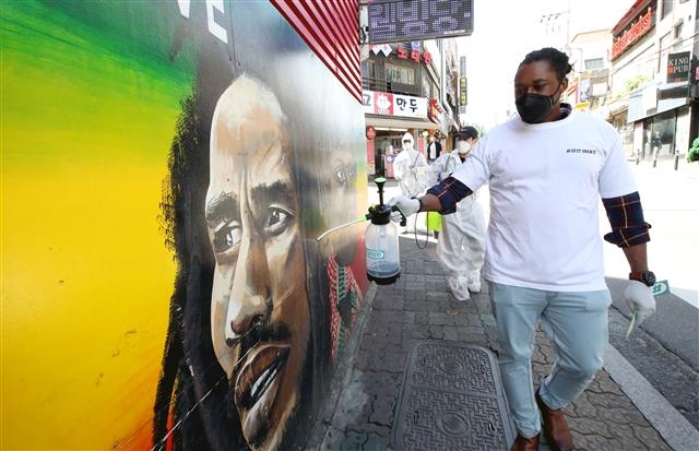 거리에서 한 외국인이 소독약을 뿌리고 있다.  뉴스1
