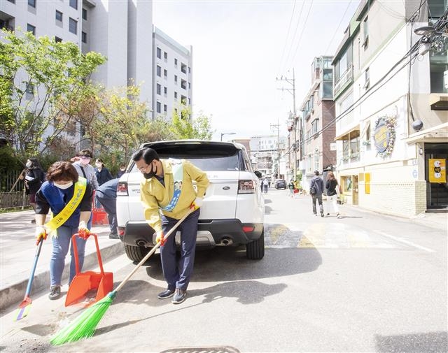 20일 성장현(오른쪽) 용산구청장이 특별방역의 날을 맞아 새마을협의회 회원들과 함께 이태원 인근에 있는 한남동 카페거리를 빗자루로 쓸고 있다. 용산구 제공