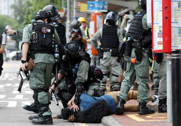 최루탄 발사기와 진압봉으로 완전 무장한 홍콩 경찰들이 24일 시내 중심가에서 홍콩보안법과 국가법 제정에 반대하는 시위대를 체포하고 있다. 홍콩 경찰은 이날 오후 수천명의 시위대가 번화가인 코즈웨이베이 지역에 모이자마자 최루탄, 물대포, 장갑차 등을 동원했고 시위대 100여명을 체포했다. 일부 시위대는 성조기를 들었고 2014년 벌어진 대규모 민주화 시위 ‘우산혁명’의 상징인 우산을 쓰기도 했다. 홍콩 AP 연합뉴스
