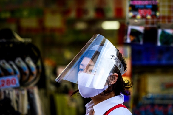 일본 도쿄의 스가모 지역 쇼핑거리에서 24일 한 가게 직원이 마스크와 얼굴 보호대를 착용한 채 가게 밖에서 고객들을 기다리고 있다. 2020.5.24  EPA 연합뉴스