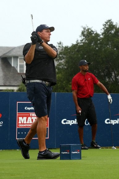 필 미컬슨(왼쪽)이 25일 미국 플로리다주 메달리스트 골프클럽에서 열린 라이벌인 ‘골프 황제’ 타이거 우즈와의 맞대결 이벤트에서 우즈가 지켜보는 가운데 1번홀 티샷을 날리고 있다. 호브 사운드(미 플로리다) EPA 연합뉴스