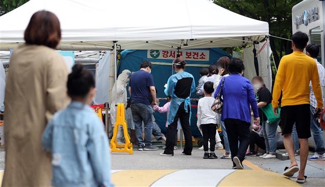 서울 강서구 한 미술학원 강사가 지난 24일 신종 코로나바이러스 감염증(코로나19) 확진 판정을 받아 인근 초등학교 2곳이 등교 중지 결정을 내린 가운데 해당 학원에 다닌 유치원생 1명도 같은날 확진 판정을 받은 것으로 확인됐다.  사진은 25일 오후 서울 강서구보건소 선별진료소를 찾은 시민들과 어린이들이 검사 순서를 기다리고 있다. 2020.5.25/뉴스1