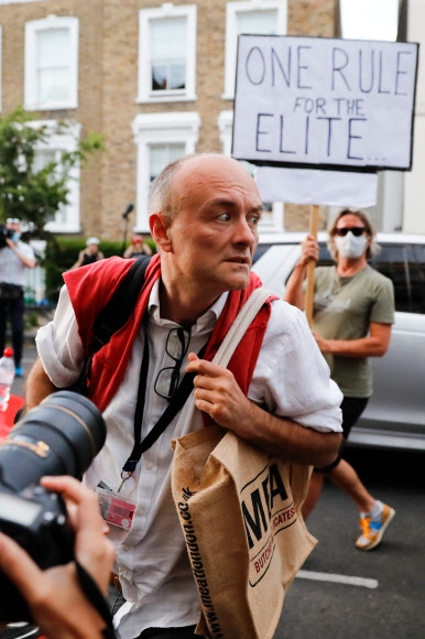 자택 격리 지침을 어겼다는 논란에 휩싸여 사퇴 압력을 받고 있는 영국 총리 수석 보좌관 도미닉 커밍스가 25일(현지시간) 런던 자택앞에 진을 친 취재진과 기자회견을 가진 뒤 시위자들이 몰려들자 피하려 하고 있다. 런던 AFP 연합뉴스