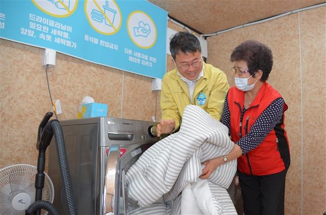 서양호(왼쪽) 서울 중구청장이 지난 20일 서울 중구 중림종합사회복지관 1층 주차장에 마련된 ‘중림행복빨래방’에서 도우미와 함께 건조된 이불 빨래를 수거하고 있다. 중구 제공