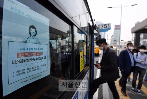 코로나19 감염 확산을 막기 위해 정부가 전국 대중교통 이용 시 마스크 착용을 의무화하는 조치를 시행한 첫날인 26일 서울 중구 서울역 앞 버스 정류장에서 한 시민이 마스크를 쓰고 버스를 타고 있다. 박윤슬 기자 seul@seoul.co.kr