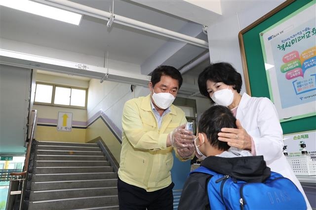 27일 서울 관악구 신성초를 찾은 박준희(왼쪽) 관악구청장이 한 학생의 체온을 재고 있다. 관악구 제공