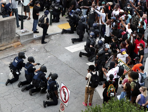 1일(현지시간) 진압복을 입고 무장한 경찰들이 시위대 앞에서 무릎을 꿇고 있다. AP통신
