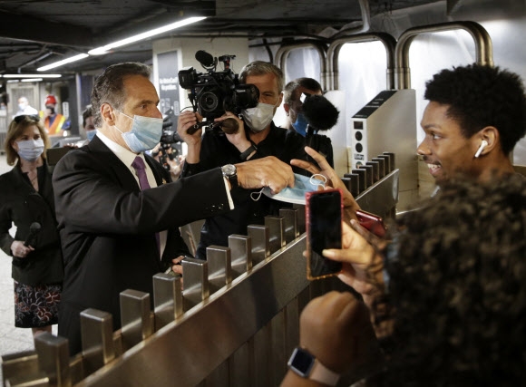 미국에서 신종 코로나바이러스 감염증(코로나19)으로 가장 큰 타격을 입었던 뉴욕 시가 8일(현지시간) 1단계 경제 정상화 조치에 돌입했다. 앤드루 쿠오모 뉴욕 주지사는 뉴욕시 맨해튼의 한 지하철역을 방문한 가운데 마스크를 쓰지않은 시민에게 마스크를 건네고 있다. UPI 연합뉴스