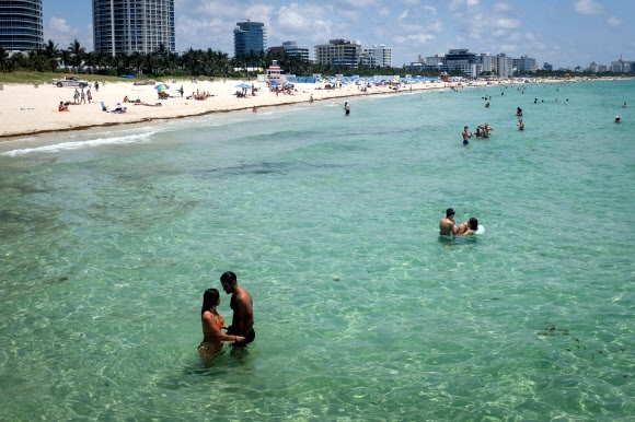 미국 플로리다 주민들이 10일(현지시간) 코로나19 여파로 3개월여 문을 닫았다 재개방한 마이애미 비치  바닷가에서 수영을 즐기며 휴식을 취하고 있다. 로이터 연합뉴스