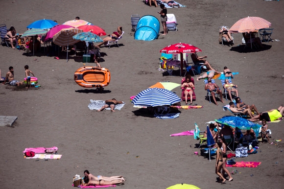 14일(현지시간) 스페인 말라가의 빅토리아 비치를 찾은 시민들이 일광욕을 즐기고 있다. EPA 연합뉴스