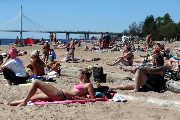 시민들이 14일(현지시간) 러시아 상트페테르부르크의 크레스톱스키 섬 해변가에서 일광욕을 즐기고 있다. 타스 연합뉴스