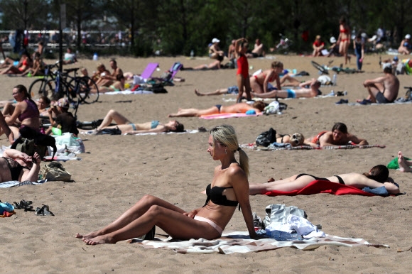시민들이 14일(현지시간) 러시아 상트페테르부르크의 크레스톱스키 섬 해변가에서 일광욕을 즐기고 있다. 타스 연합뉴스