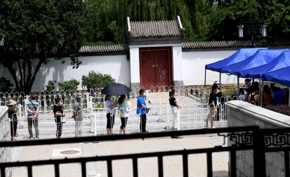중국 베이징에서 16일 신파디 시장 근처에 살거나 방문했던 사람들이 마스크를 쓰고 코로나 검사를 받기 위해 줄을 서 있다. 연합뉴스
