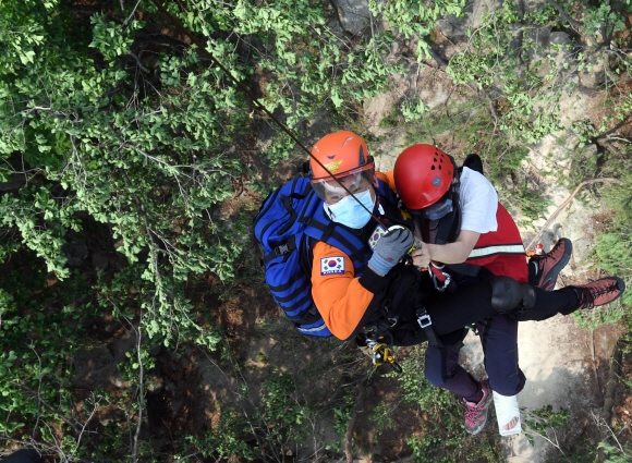 수락산에서 구급대원이 지상에서 구조한 환자와 함께 헬기로 올라오고 있다.