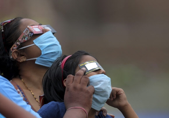 부분 일식이 진행된 21일 인도 하이데라바드 여성들이 마스크를 쓴 채 필터판을 이용해 10년 뒤에나 보게 될 우주쇼를 관측하고 있다. 하이데라바드 AP 연합뉴스 
