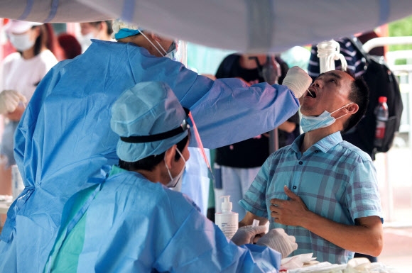 23일 중국 베이징의 한 야외 진료소에서 방역당국 직원들이 코로나19 검체 검사를 진행하고 있다. 2020.6.23  AFP 연합뉴스