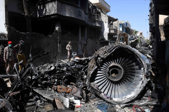 지난달 22일 파키스탄 카라치 진나국제공항 근처 주택가에 파키스탄 국제항공(PIA) PK 8303편 여객기가 추락한 이틀 뒤 안전요원들이 추락 잔해 옆에 서 있다.  AFP 자료사진 연합뉴스 