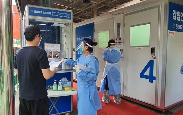 지난 26일 서울 중구보건소 관계자(오른쪽)가 보건소 앞에 마련된 이동식 워킹스루 검체채취부스에서 한 주민에게 검사방식을 설명하고 있다. 중구 제공