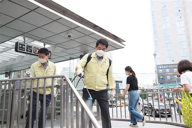 박준희(가운데) 관악구청장이 취임 2주년을 맞은 지난 1일 출근길에 직원들과 함께 지하철역 손잡이를 소독하고 있다. 관악구 제공