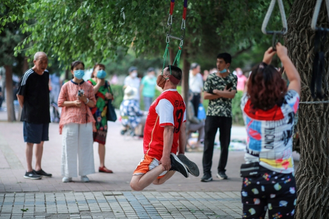 한 남성이 5일(현지시간) 중국 랴오닝성 선양에서 나무에 얼굴을 매달고 운동을 하고 있다. AFP 연합뉴스