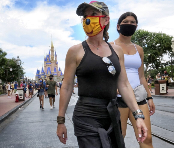 미국 플로리다주 올랜도의 디즈니월드가 재개장한 11일(현지시간) 방문객들이 마스크를 쓴 채로 이동하고 있다. AP 연합뉴스