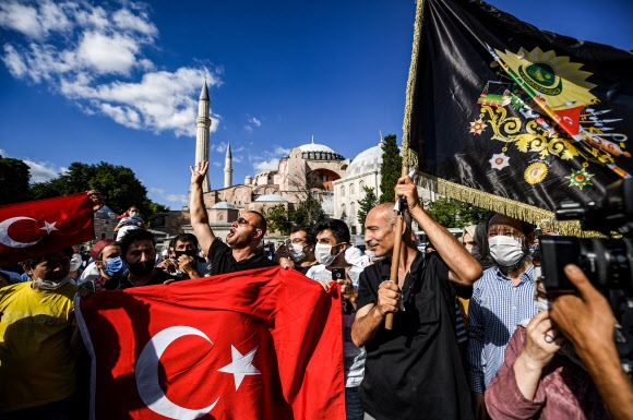 터키 최고행정법원이 이스탄불에 있는 유네스코 세계유산인 성소피아 대성당을 85년 만에 박물관에서 사원으로 되돌리는 결정을 내린 10일(현지시간) 이를 지지하는 시민들이 대성당 밖에서 이슬람 깃발을 흔들며 환호하고 있다. 이스탄불 AFP 연합뉴스