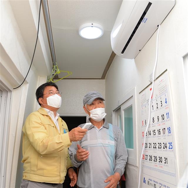 서양호(왼쪽) 서울 중구청장이 지난 13일 중구 신당동 개미골목의 한 원룸에 사는 독거노인을 위해 에어컨을 직접 설치한 뒤 작동해 보고 있다. 중구 제공