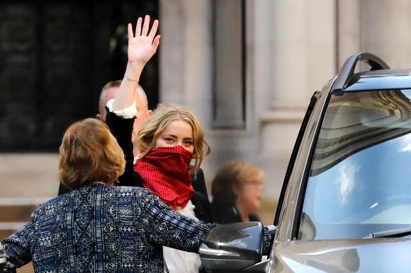 미국출신 배우 앰버 허드가 17일(현지시간) 영국 런던 고등법원에서 열린 전 남편 조니 뎁이 더 선을 상대로 제기한 명예훼손 소송 관련 재판에 참석한 후 떠나며 손을 흔들고 있다. AFP 연합뉴스