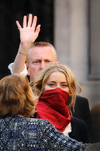 미국출신 배우 앰버 허드가 17일(현지시간) 영국 런던 고등법원에서 열린 전 남편 조니 뎁이 더 선을 상대로 제기한 명예훼손 소송 관련 재판에 참석한 후 떠나며 손을 흔들고 있다. AFP 연합뉴스