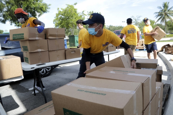 지난 7일(현지시간) 자원봉사자들이 이웃에게 무료로 배급할 음식을 나르고 있다. AP통신