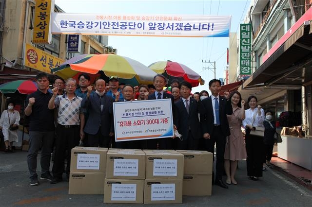 한국승강기안전공단 임직원들이 지난달 진주중앙시장 상인들에게 휴대용 소화기 300대를 기증하고 있다. 한국승강기안전공단 제공