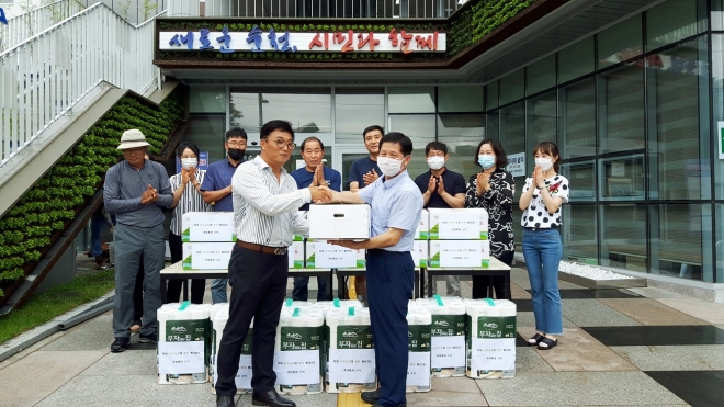 임현우 ㈜승하 대표가 손한기(오른쪽) 조곡동장에게 닭과 한약재, 과일, 휴지를 담은 100만원 상당의 권분상자를 전달하고 있다.