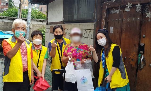 성북구 길음2동 주민들이 지난 22일 한 노인의 집을 찾아 삼계탕과 반찬 등을 전달하고 함께 기념사진을 찍고 있다. 성북구 제공