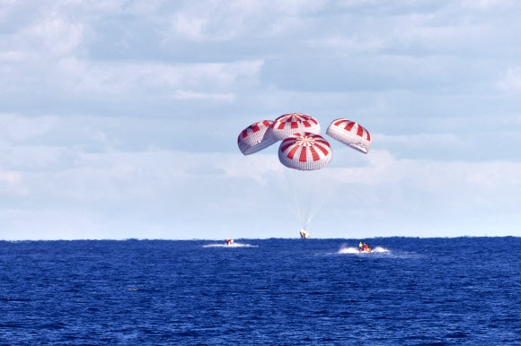 두 달여 국제우주정거장(ISS)에 머무르던 스페이스X의 유인 우주 캡슐이 3일(한국시간) 미국 플로리다주 펜사콜라 남쪽 바다에 메인 낙하산 4개를 펼친 채 물에 들어가는 스플래시다운 방식으로 안착하고 있다. NASA 제공 AP 연합뉴스