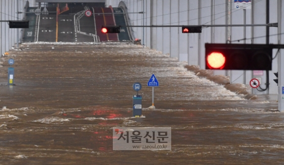 잠수교도… 집값도… 빨간불 3일 서울 잠수교가 불어난 한강 물에 잠겨 있다. 잠수교는 한강 수위 상승으로 지난 2일 오후부터 전면 통제되고 있다. 이날 수도권을 비롯한 중부지역에 물폭탄 수준의 폭우가 쏟아지면서 산사태 등으로 많은 사상자가 발생하고 도로와 주택이 물에 잠기는 등 피해가 속출하고 있다. 기상청은 5일까지 중부지역에 누적강수량 100~300㎜, 최대 500㎜ 이상의 많은 비가 내릴 것으로 예보했다. 박지환 기자 popocar@seoul.co.kr