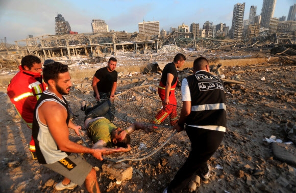 레바논 수도 베이루트 항구에서 4일(현지시간) 대형 폭발 참사가 일어난 후 현장에서 구급대원과 시민들이 부상자를 들것에 실어 이송하고 있다. 베이루트 AFP 연합뉴스
