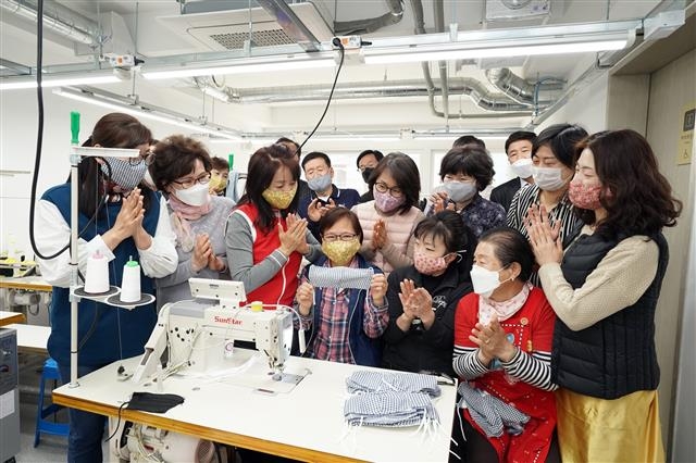 성북구 보문동 주민들이 1만 6000번째 마스크를 들고 기뻐하고 있다. 이들은 보문동 이웃 1만 6000명 모두에게 면마스크 1장씩을 나눠 줬다.  성북구 제공