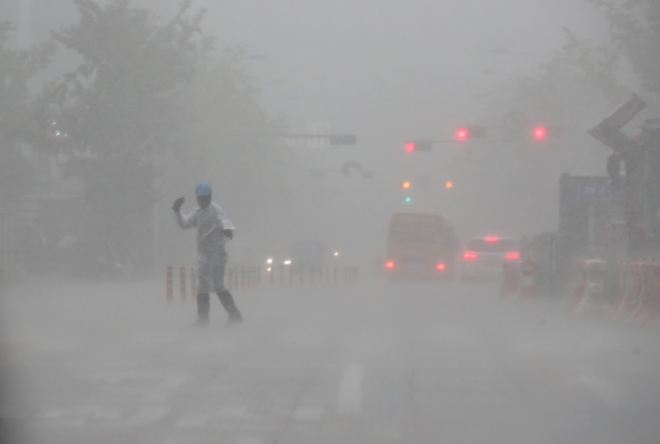사진은 지난해 8월 서울 지역에 비가 많이 내린 날에 도로보수원이 도로를 지나는 차량들에 수신호를 보내고 있는 모습. 연합뉴스