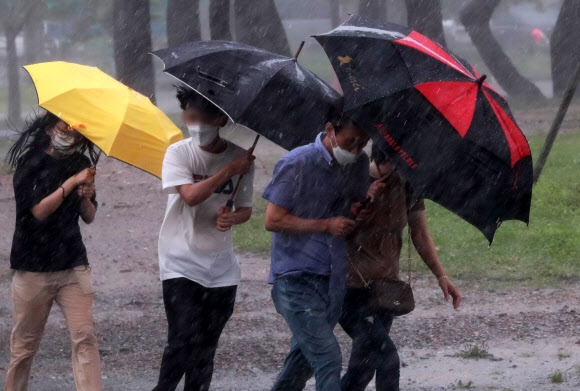 태풍 장미가 상륙한 10일 오후 부산 해운대 해수욕장 부근에서 시민들이 비바람을 피해 우산을 쓰고 걸어가고 있다. 2020.8.10  연합뉴스