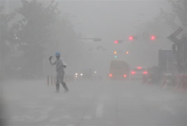 사진은 지난해 8월 서울에 비가 많이 내린 날에 도로보수원이 도로를 지나는 차량들에 수신호를 보내고 있는 모습. 연합뉴스