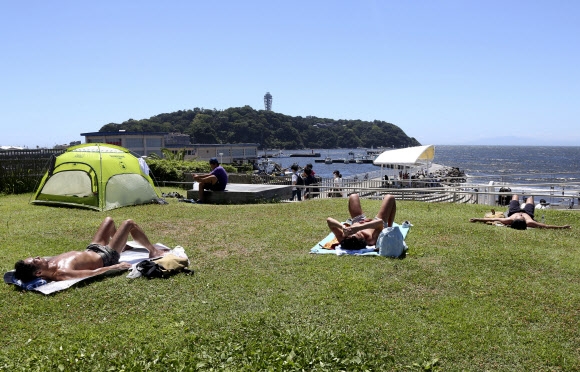 11일(현지시간) 일본 도쿄 인근 후지사와의 한 해변에서 시민들이 일광욕을 즐기며 휴식을 취하고 있다. AP 연합뉴스