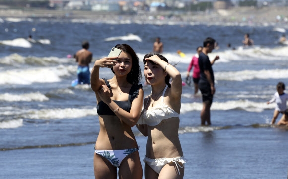 11일(현지시간) 일본 도쿄 인근 후지사와의 한 해변에서 시민들이 셀카를 찍고 있다. AP 연합뉴스